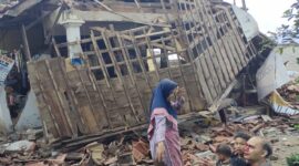 Foto salah satu keluarga korban selamat gempa Cianjur di depan bangunan roboh