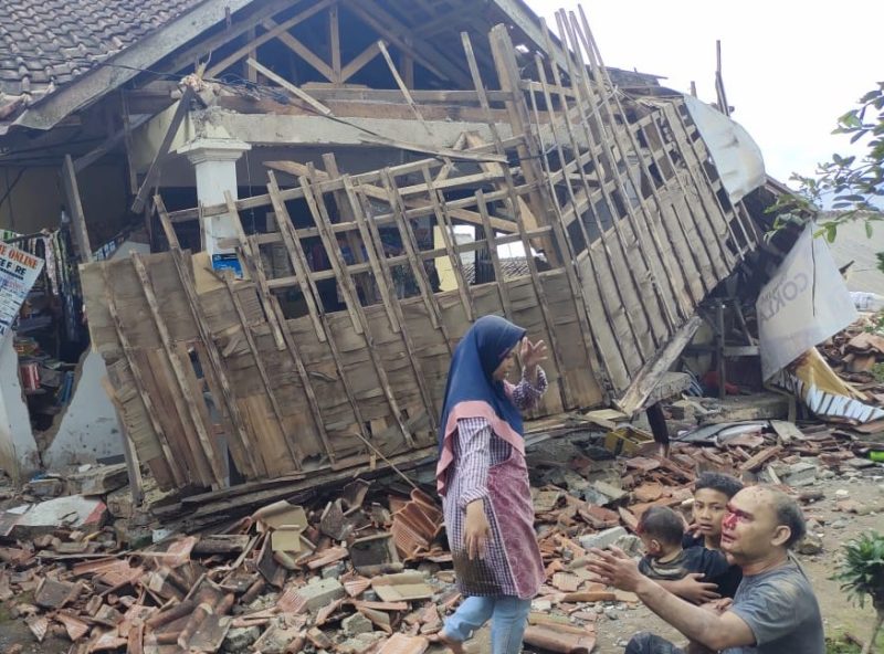 Foto salah satu keluarga korban selamat gempa Cianjur di depan bangunan roboh