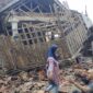 Foto salah satu keluarga korban selamat gempa Cianjur di depan bangunan roboh