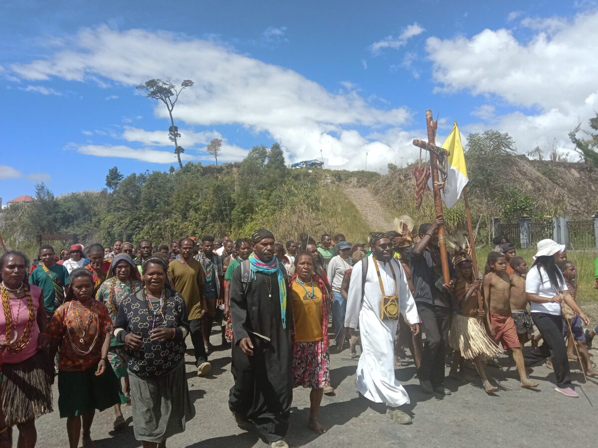 Suasana perarakan Salib Yesus yang berbusana Koteka dan bendera perdamaian di ibukota Sugapa yang dipimpin langsung oleh Koordinator Kepemudaan Keuskupan Timika,Pastor Benyamin Magai, Pr (berjubah putih) dan Koordinator Kepemudaan Dekenat Moni-Puncak,Pastor Yoseph Bunai,Pr (jubah hitam) pada Sabtu, (03/6/2023)/foto:ist.