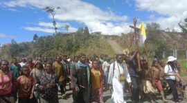 Suasana perarakan Salib Yesus yang berbusana Koteka dan bendera perdamaian di ibukota Sugapa yang dipimpin langsung oleh Koordinator Kepemudaan Keuskupan Timika,Pastor Benyamin Magai, Pr (berjubah putih) dan Koordinator Kepemudaan Dekenat Moni-Puncak,Pastor Yoseph Bunai,Pr (jubah hitam) pada Sabtu, (03/6/2023)/foto:ist.